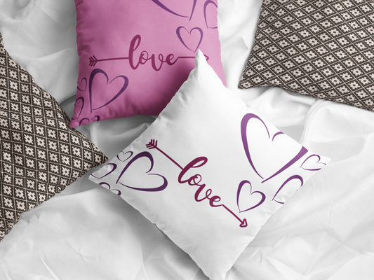 Pink and white Love Arrow pillows on bed.