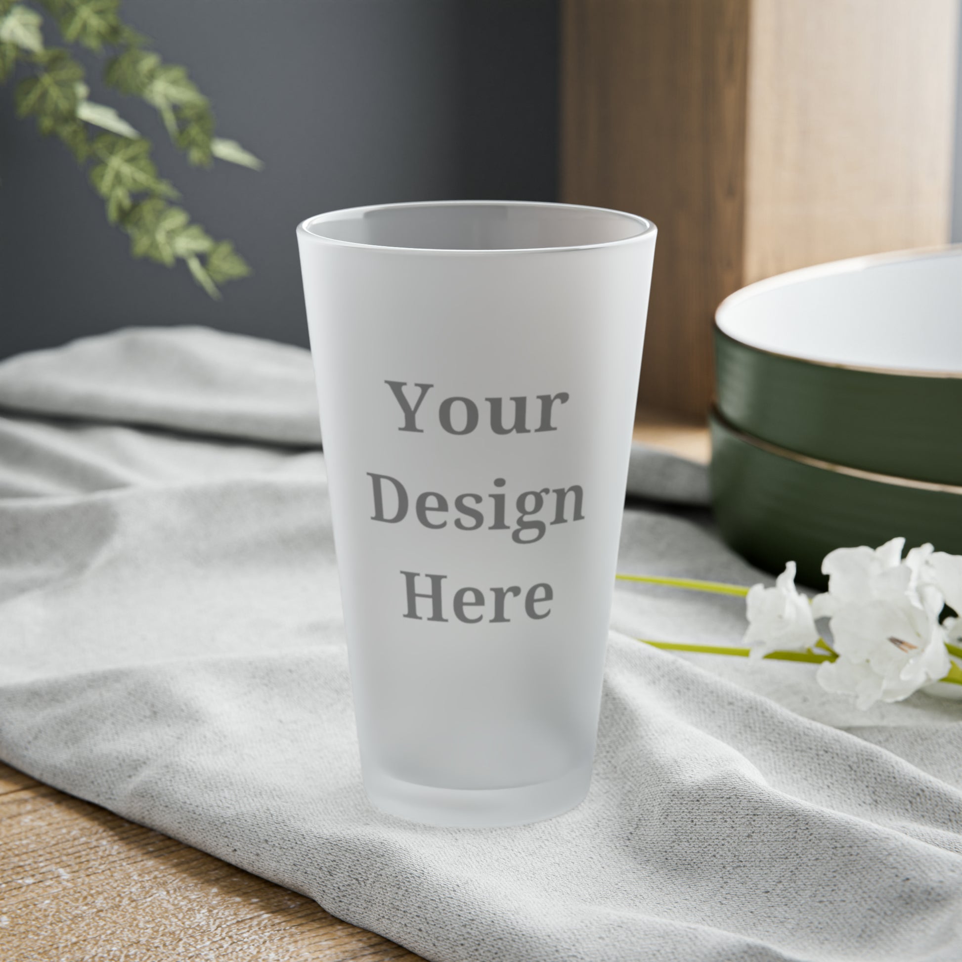 Frosted pint glass featuring “your design here” sitting on an outdoor table.