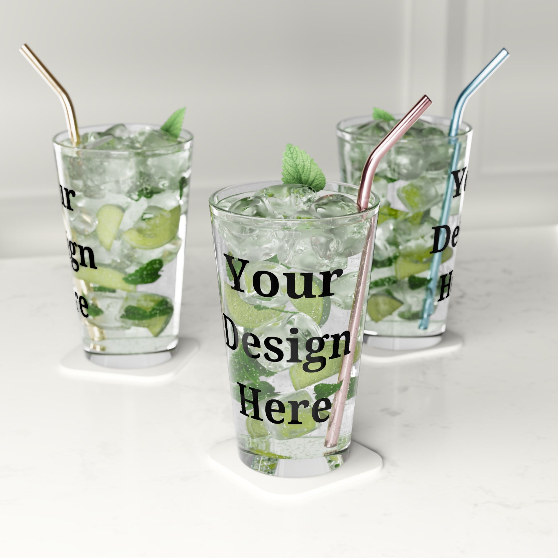 Multiple clear pint glasses featuring “your design here” filled with water on countertop.