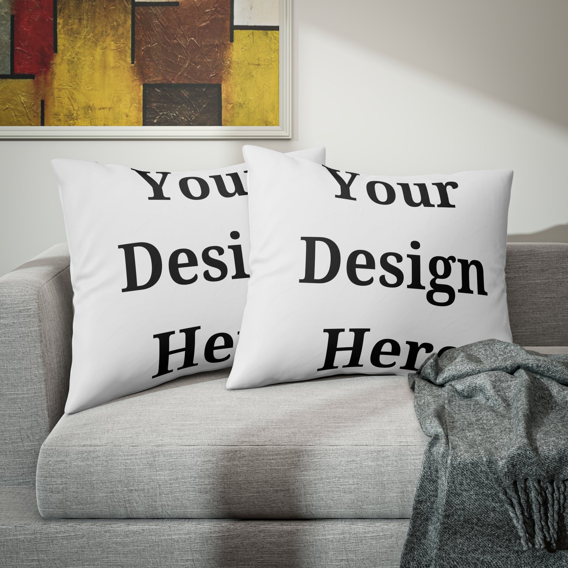 Two pillow case shams featuring “your design here” on living room couch.