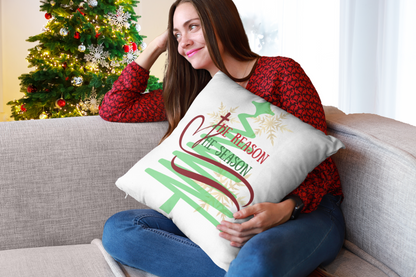 Woman sitting on couch in front of Christmas tree with white “The Reason” throw pillow.