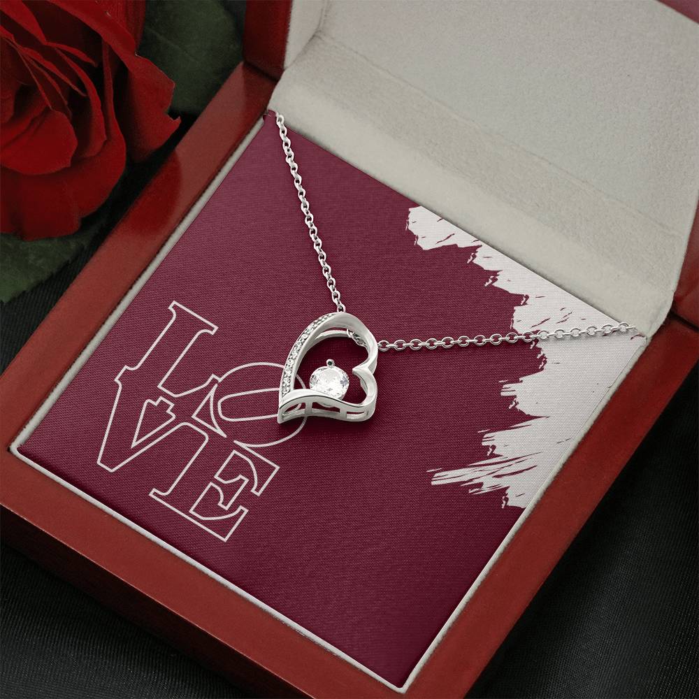 White gold heart necklace displayed in front of LOVE message card in mahogany jewelry box.