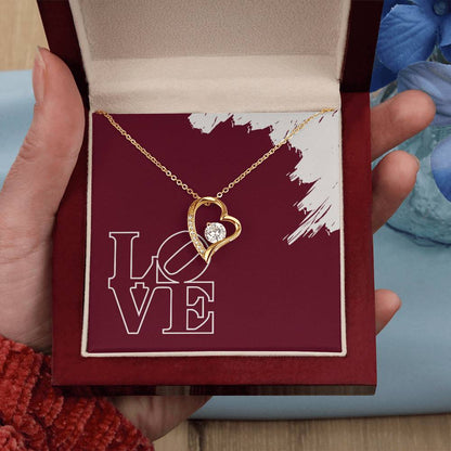 Hand holding polished gold heart pendant necklace featuring LOVE message in mahogany jewelry box.