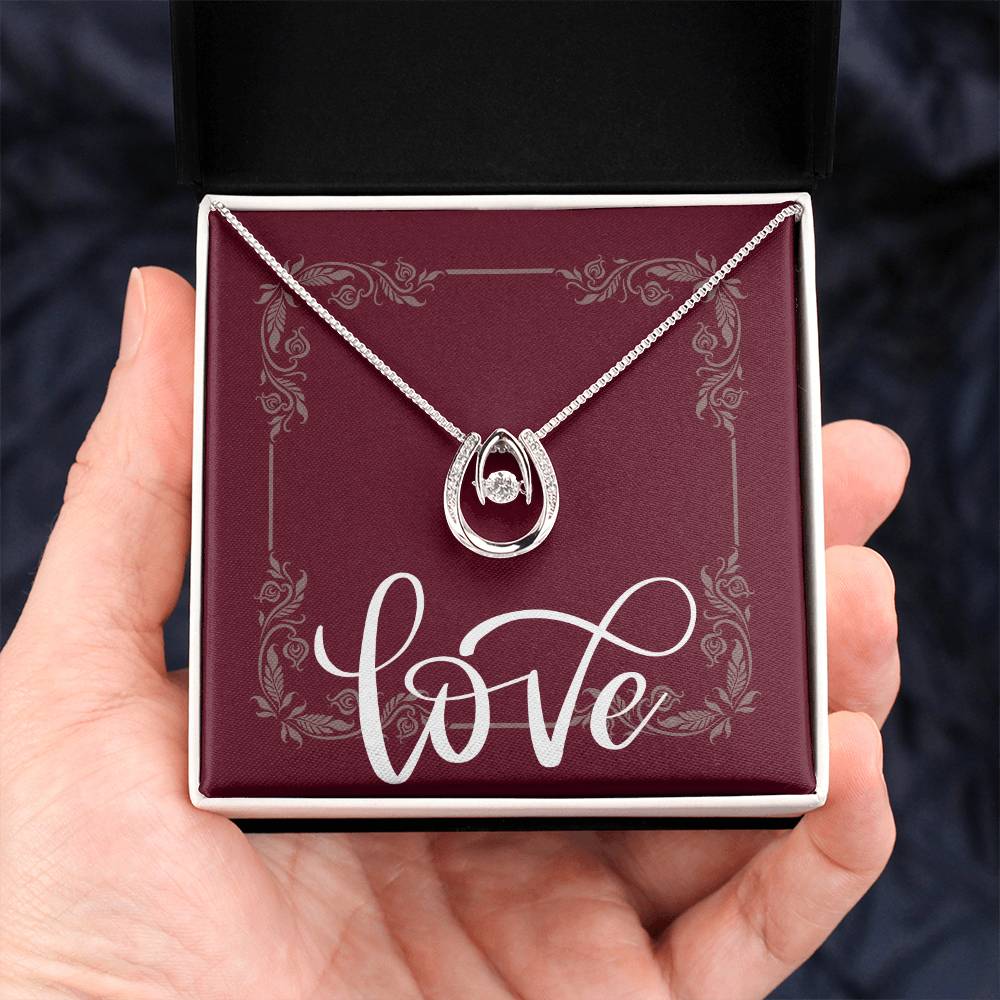 Hand holding standard black box with white gold lucky in love necklace.