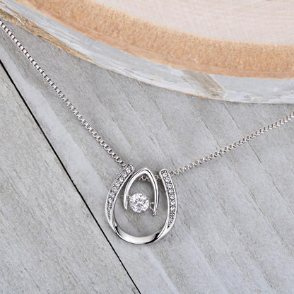 White gold Lucky in Love necklace laying on grey wood countertop.