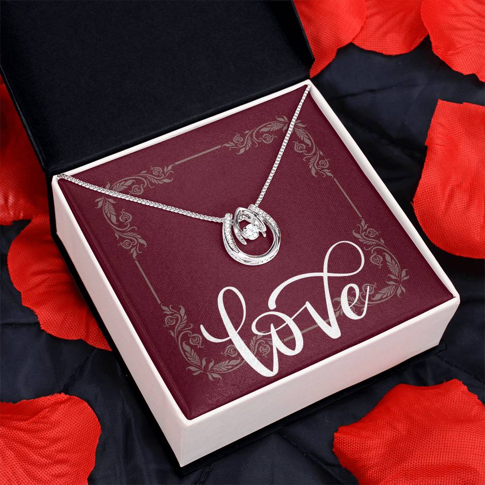 Lucky in Love necklace displayed in standard box surrounded by rose petals.