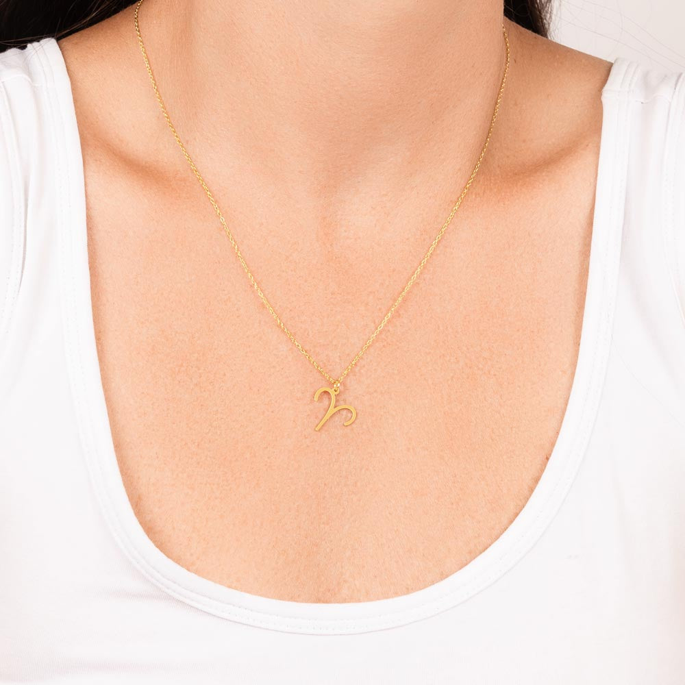 Woman wearing gold zodiac charm necklace.