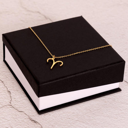 Gold Zodiac charm necklace on elegant black box.