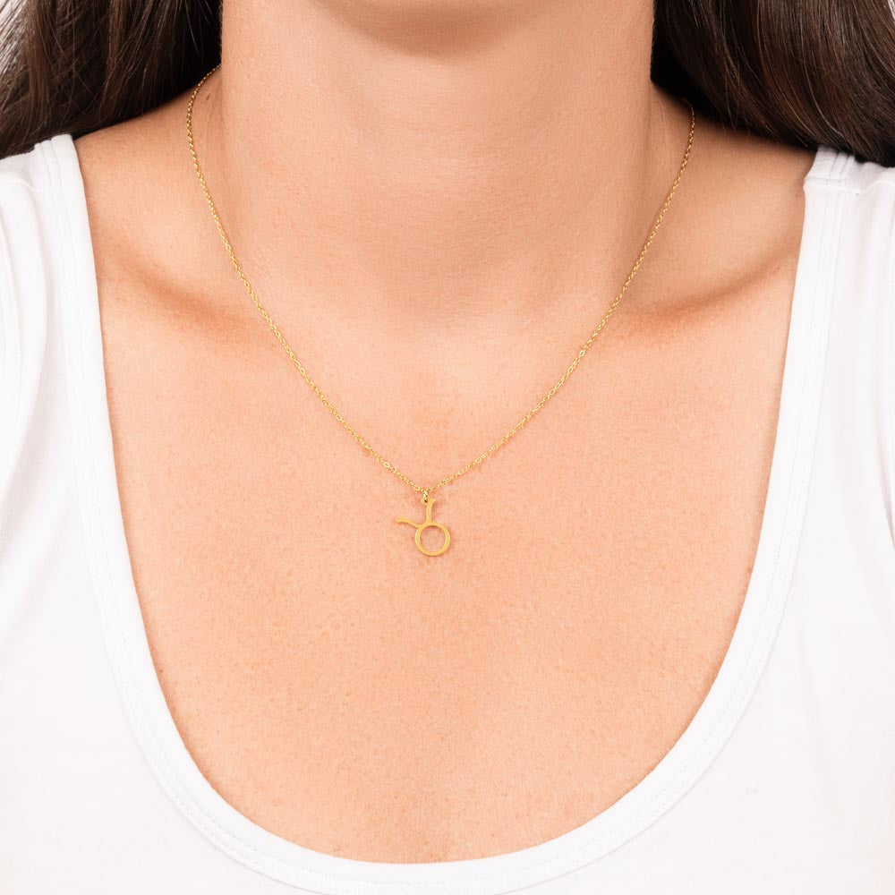 Woman wearing gold zodiac charm necklace.