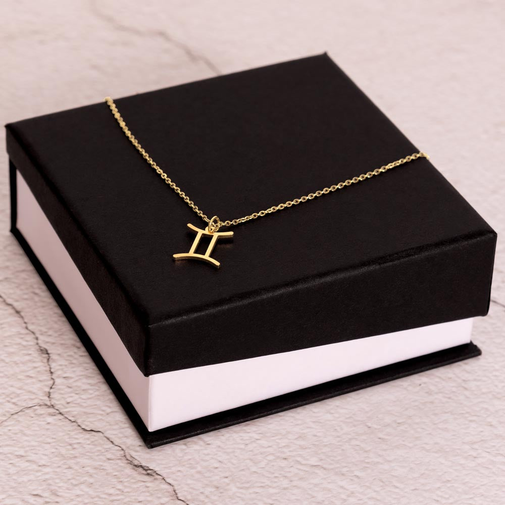 Gold Zodiac charm necklace on elegant black box.