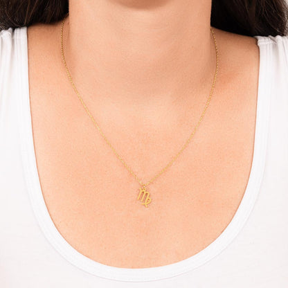 Gold Virgo Zodiac charm necklace hanging around a woman’s neck.