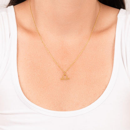 Woman wearing gold zodiac charm necklace.