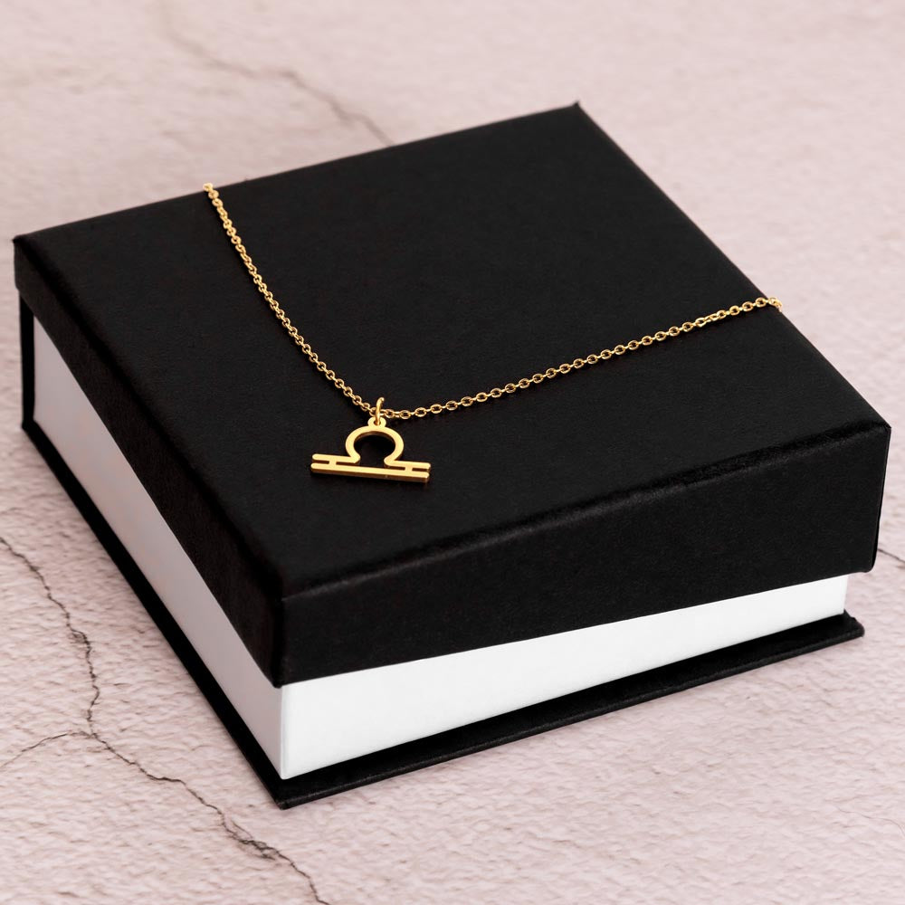 Gold Zodiac charm necklace on elegant black box.