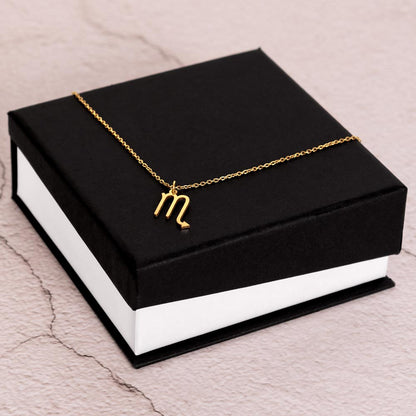 Gold Zodiac charm necklace on elegant black box.