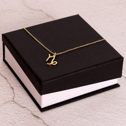 Gold Zodiac charm necklace on elegant black box.