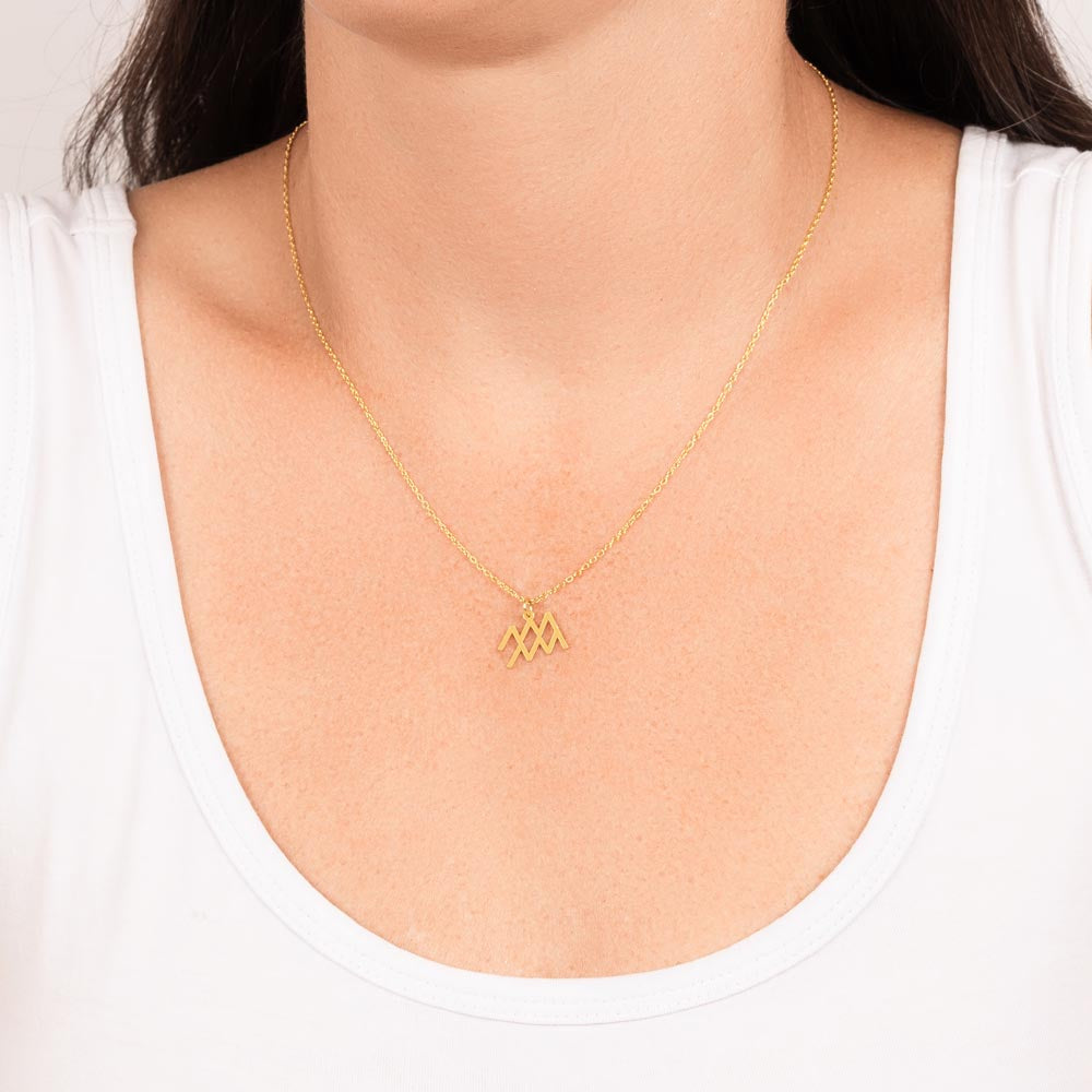 Woman wearing gold zodiac charm necklace.