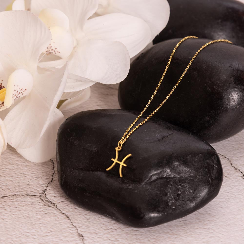 Gold Zodiac charm necklace in elegant black box, showcasing intricate astrological designs.