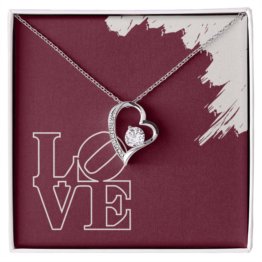 Polished Silver Heart pendant surrounding a cubic zirconia crystal hanging in front of a message card reading LOVE.