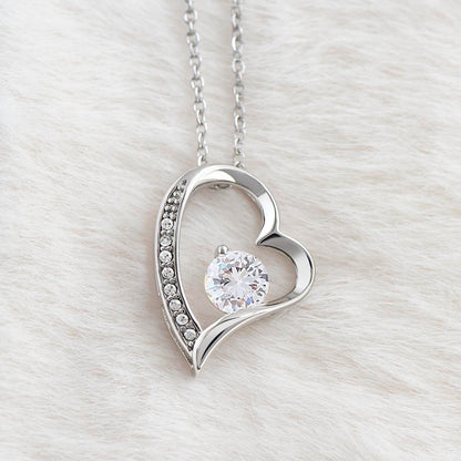 Polished White gold heart pendant surrounding cubic zirconia hanging in front of fur backing