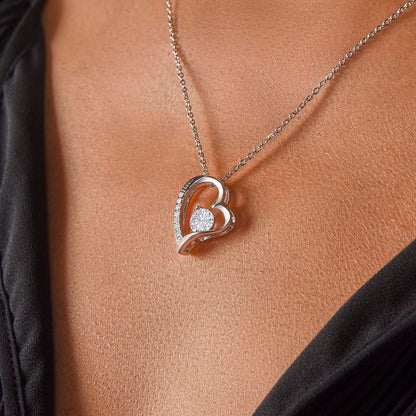 LOVE heart necklace hanging around neck of woman.