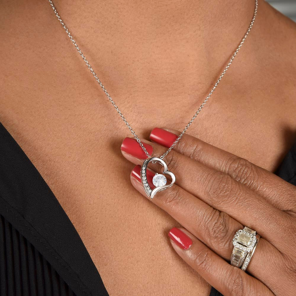 Woman holding LOVE heart necklace over her fingers.