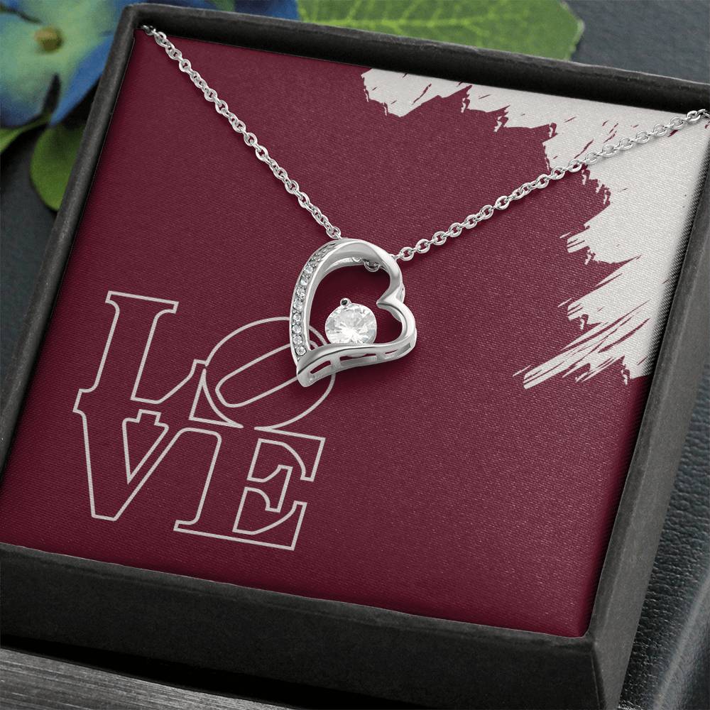 Polished Silver heart necklace with cubic zirconia hanging in front of LOVE message card in standard black jewelry box.