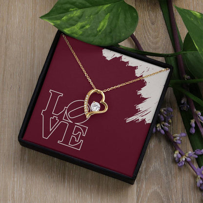 Polished Gold heart necklace surrounding cubic zirconia hanging in front of LOVE message card in standard black jewelry box.