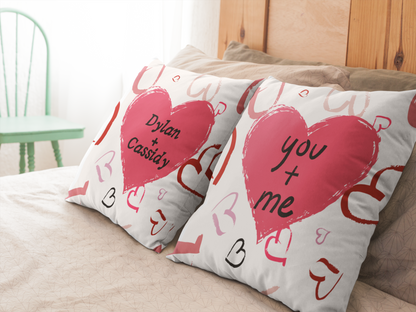 Set of “You + Me” pillows on bed in room.