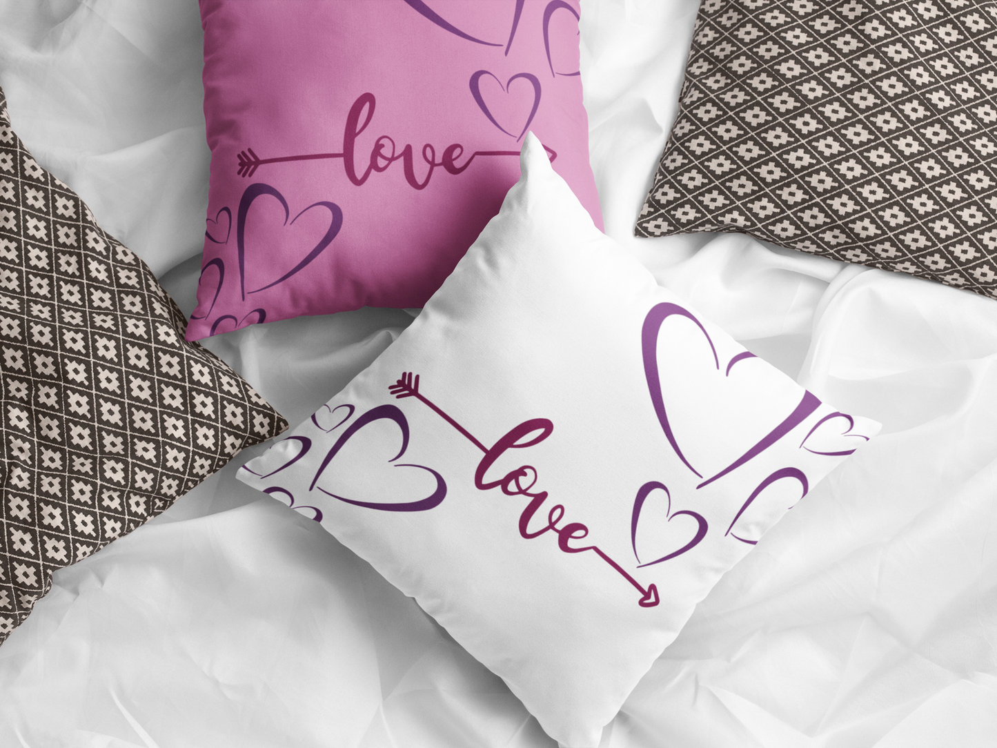 Pink and white Love Arrow pillows on bed. 